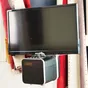 A budget LCD TV with a budget bluetooth speaker strapped to the bottom of it.